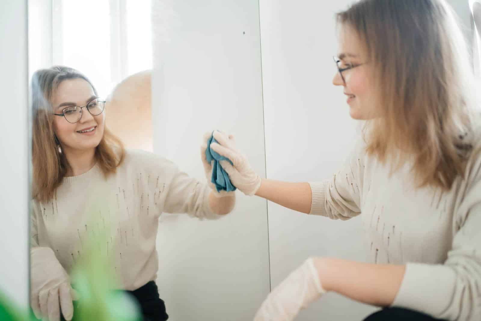 Chica limpiando un espejo